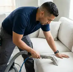 Professional upholstery cleaning technician using an extraction wand to deep-clean a fabric sofa, Aurora, CO.