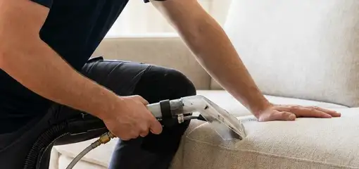 Professional upholstery cleaner deep-cleaning a fabric sofa with a handheld extraction tool, Aurora, CO.
